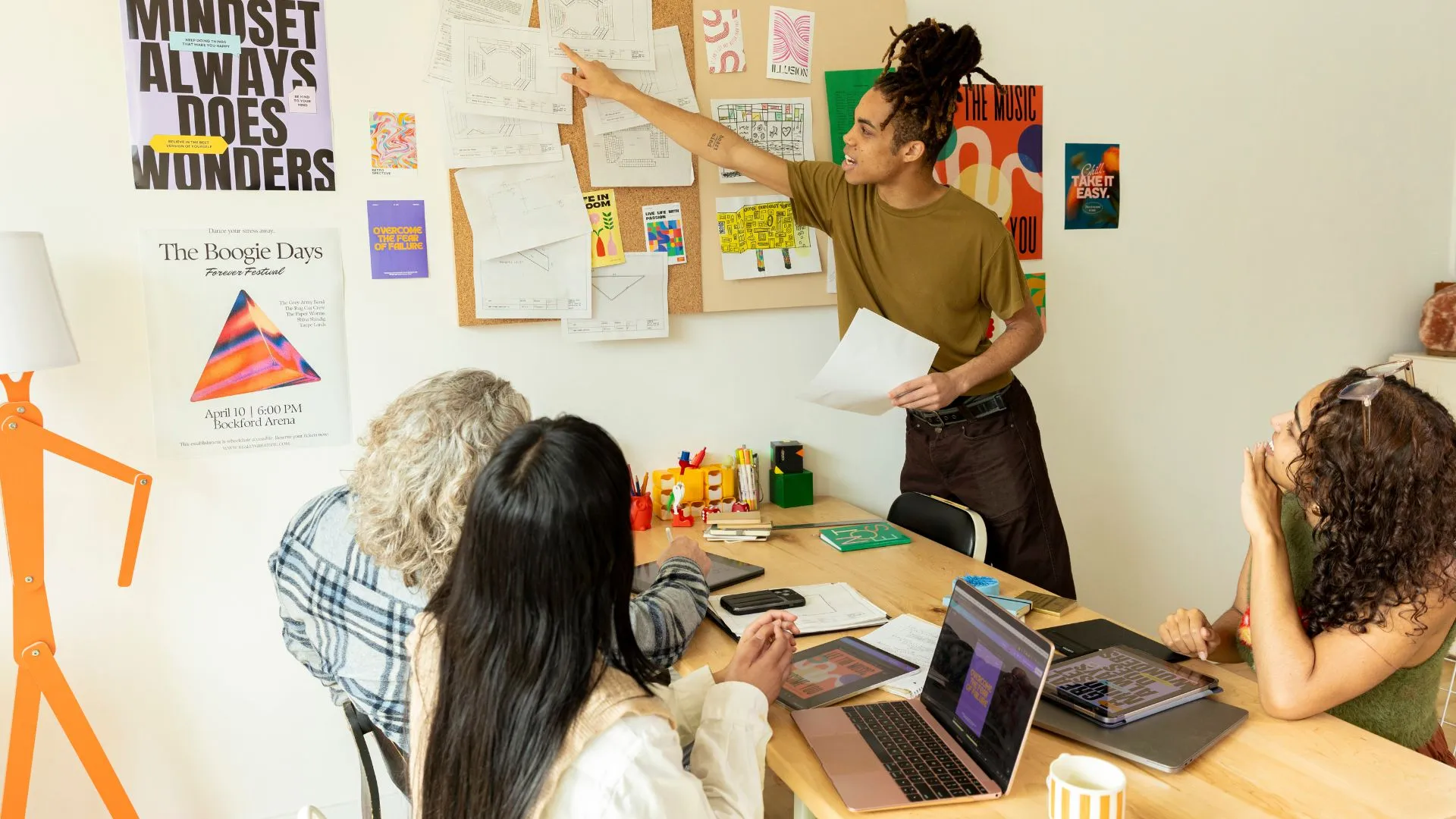 Grupo creativo en sesión de brainstorming, compartiendo ideas frente a un muro de inspiración visual y bocetos.