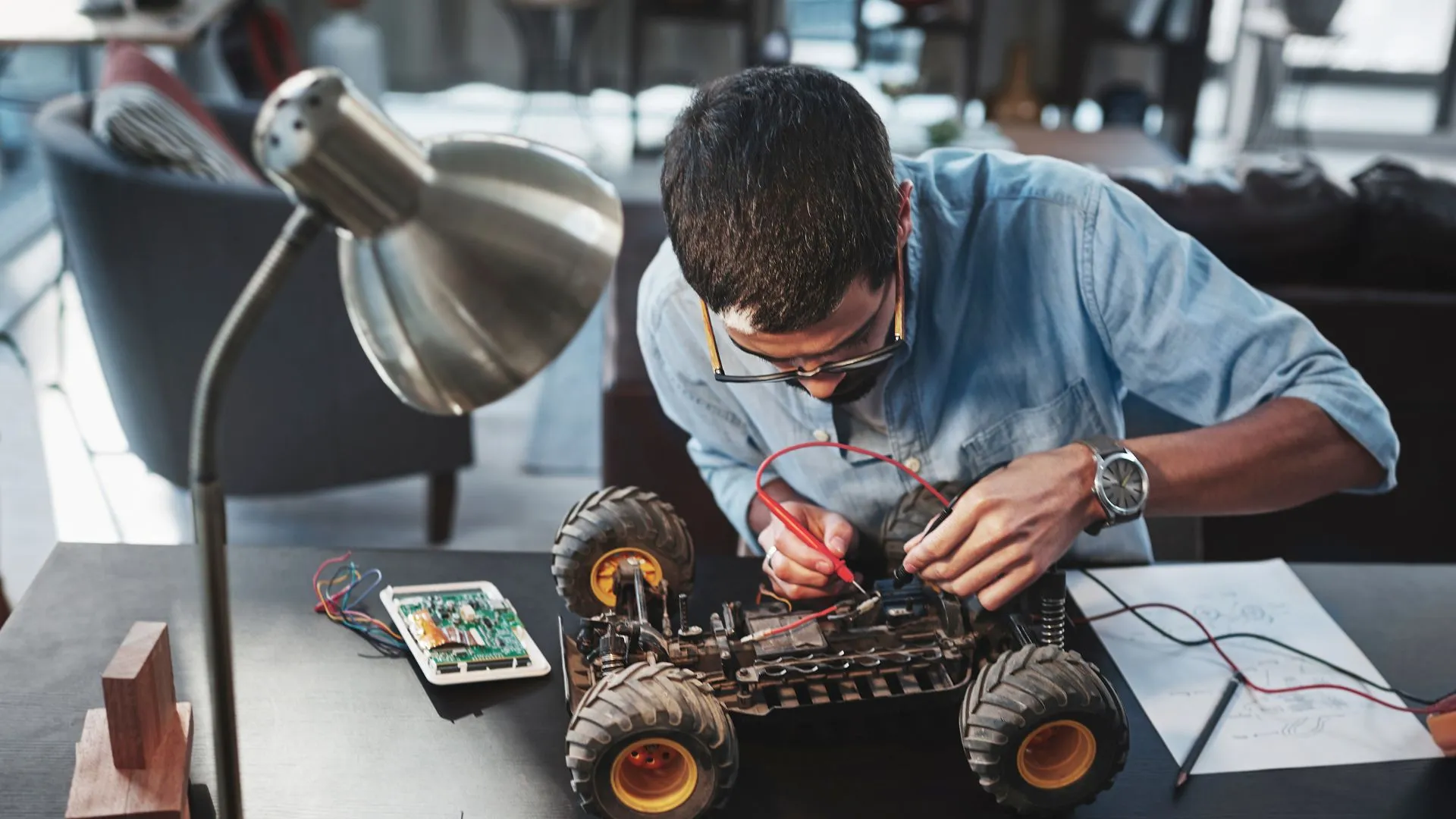 Hombre trabajando en un prototipo de vehículo con herramientas electrónicas, representando el proceso creativo detrás de los inventos revolucionarios.