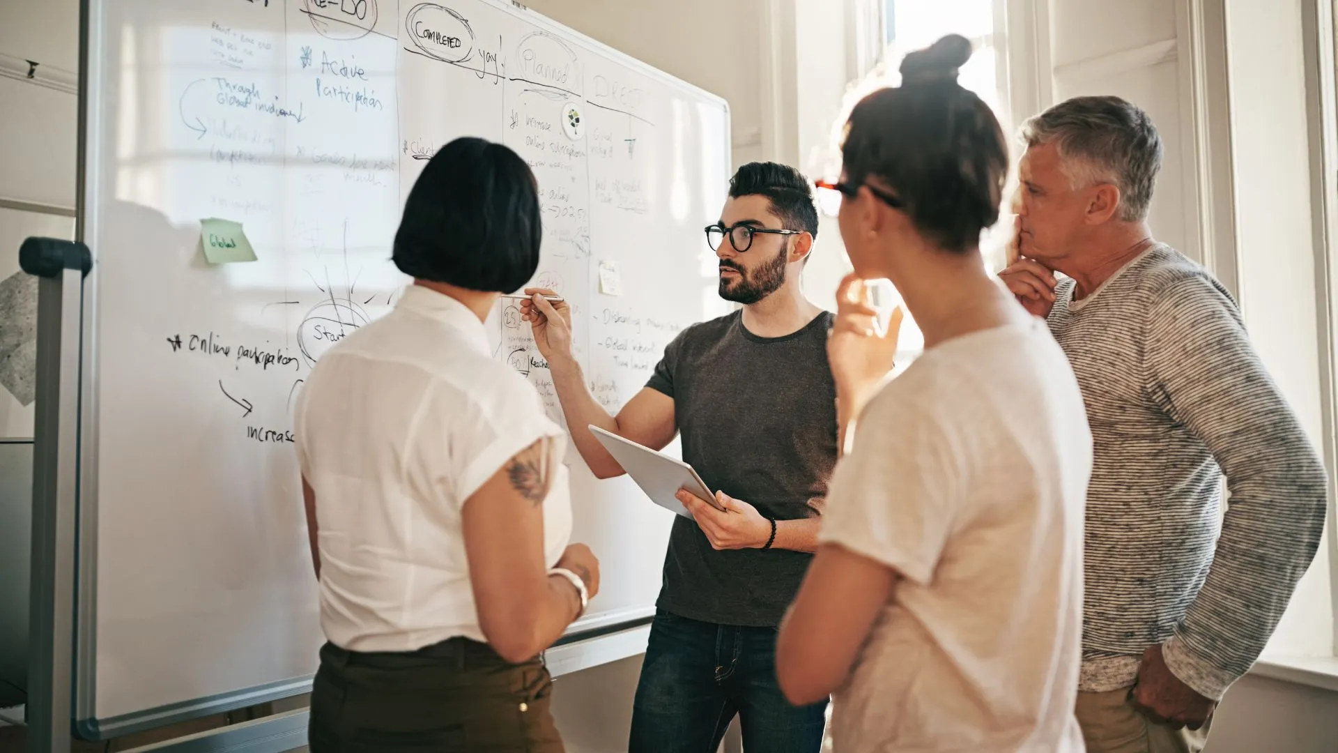 Equipo creativo analizando estrategias en una pizarra durante una reunión sobre cómo hacer campañas publicitarias efectivas.