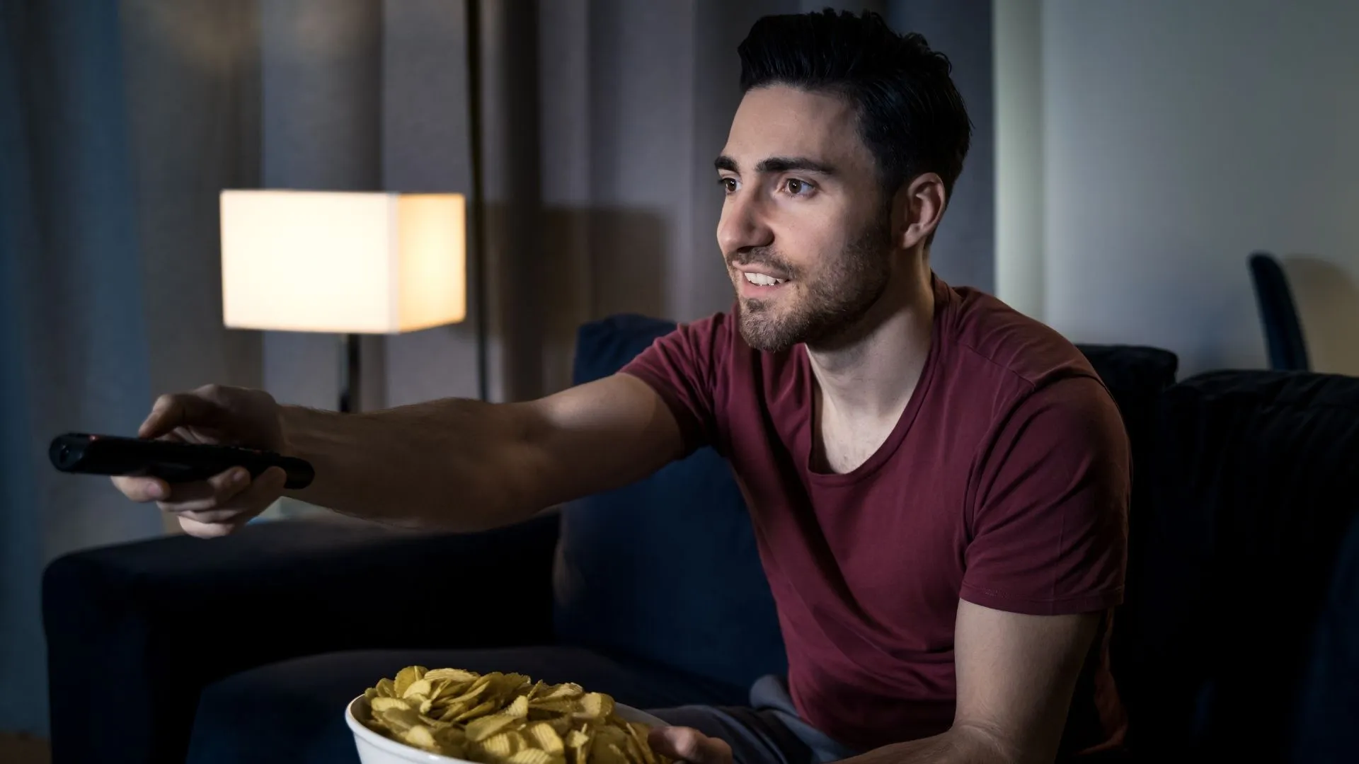 Hombre viendo televisión en casa mientras busca Películas de comedia en Amazon Prime.