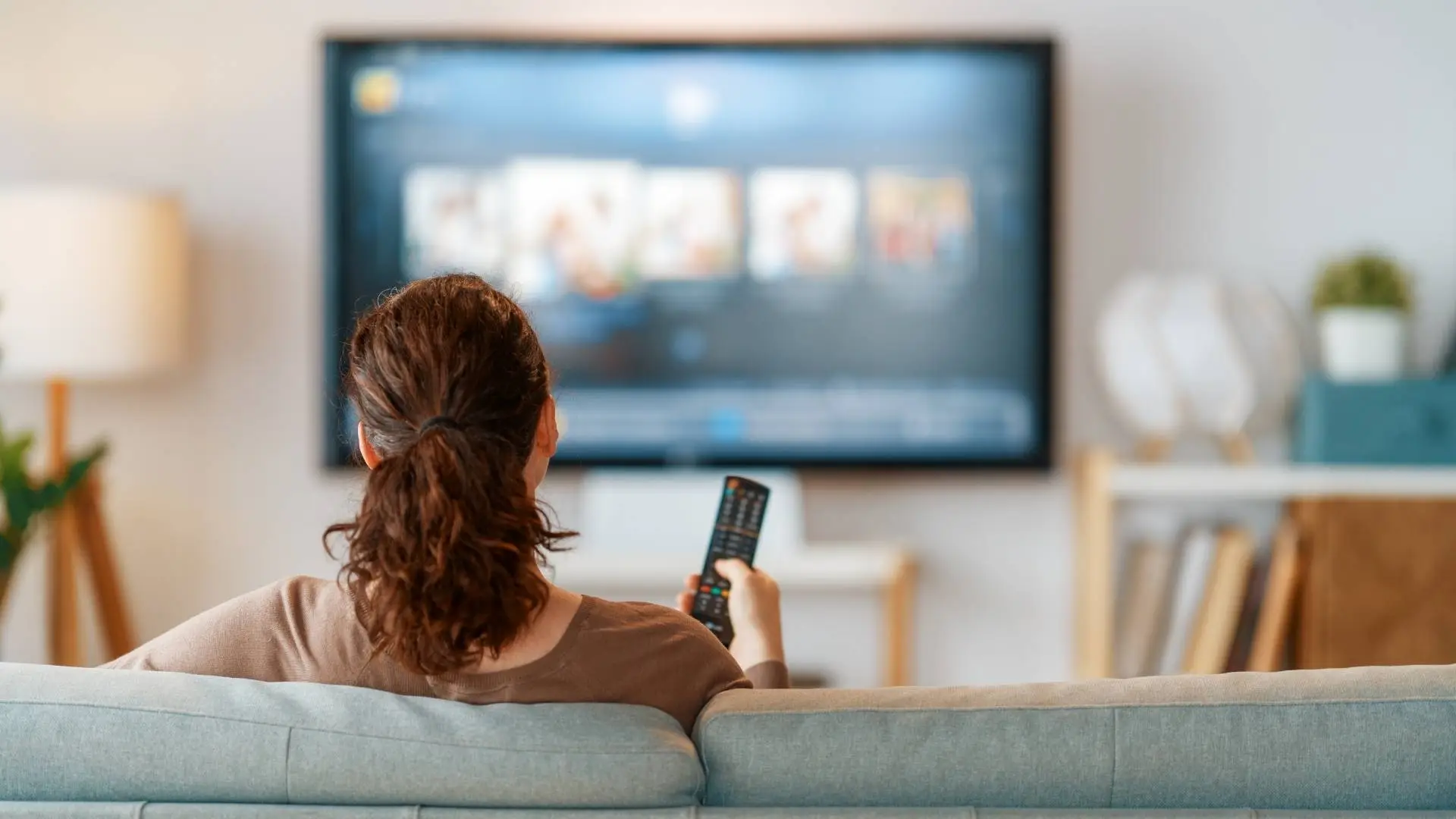 Persona viendo la televisión desde su sala mientras navega por un catálogo de películas en Apple TV.