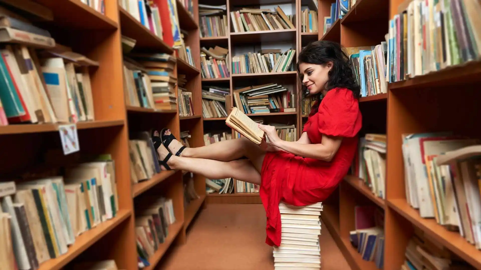 Mujer leyendo en una biblioteca mientras imagina qué personaje literario podría ser.
