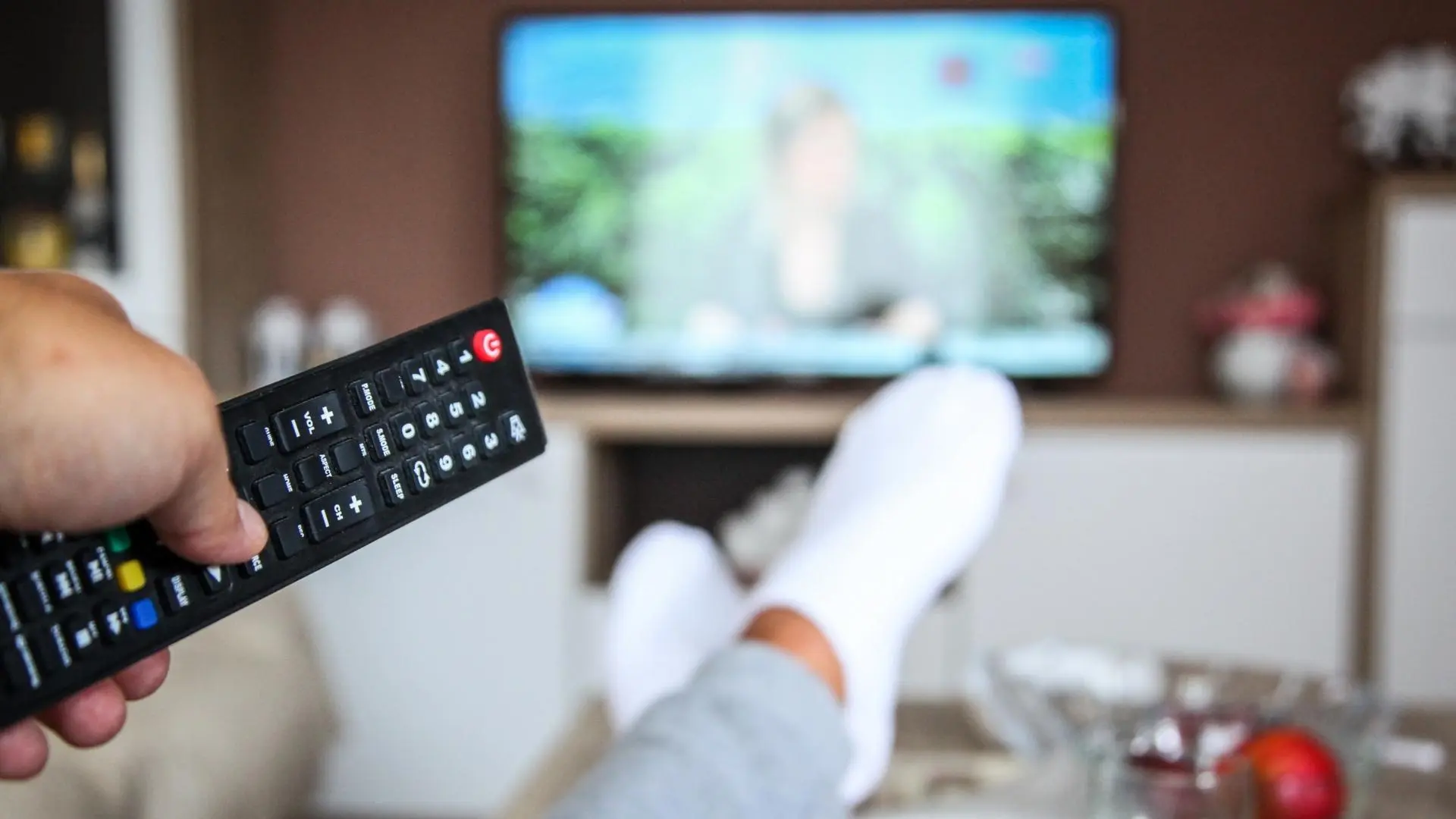 Persona descansando frente al televisor con control remoto en mano, ilustrando una guía sobre qué series hay en Apple TV.
