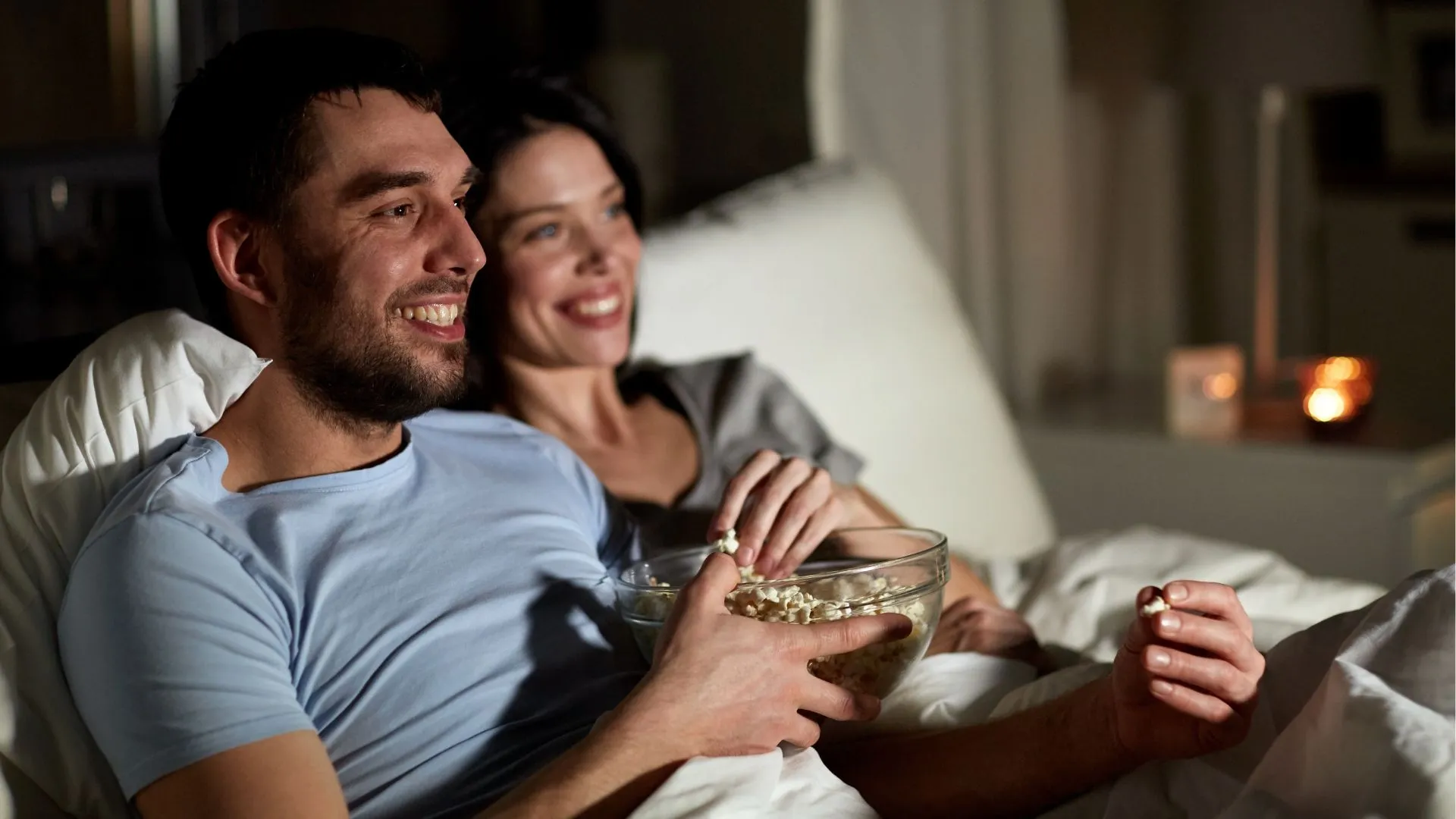 Pareja viendo películas random en casa por la noche mientras comen palomitas