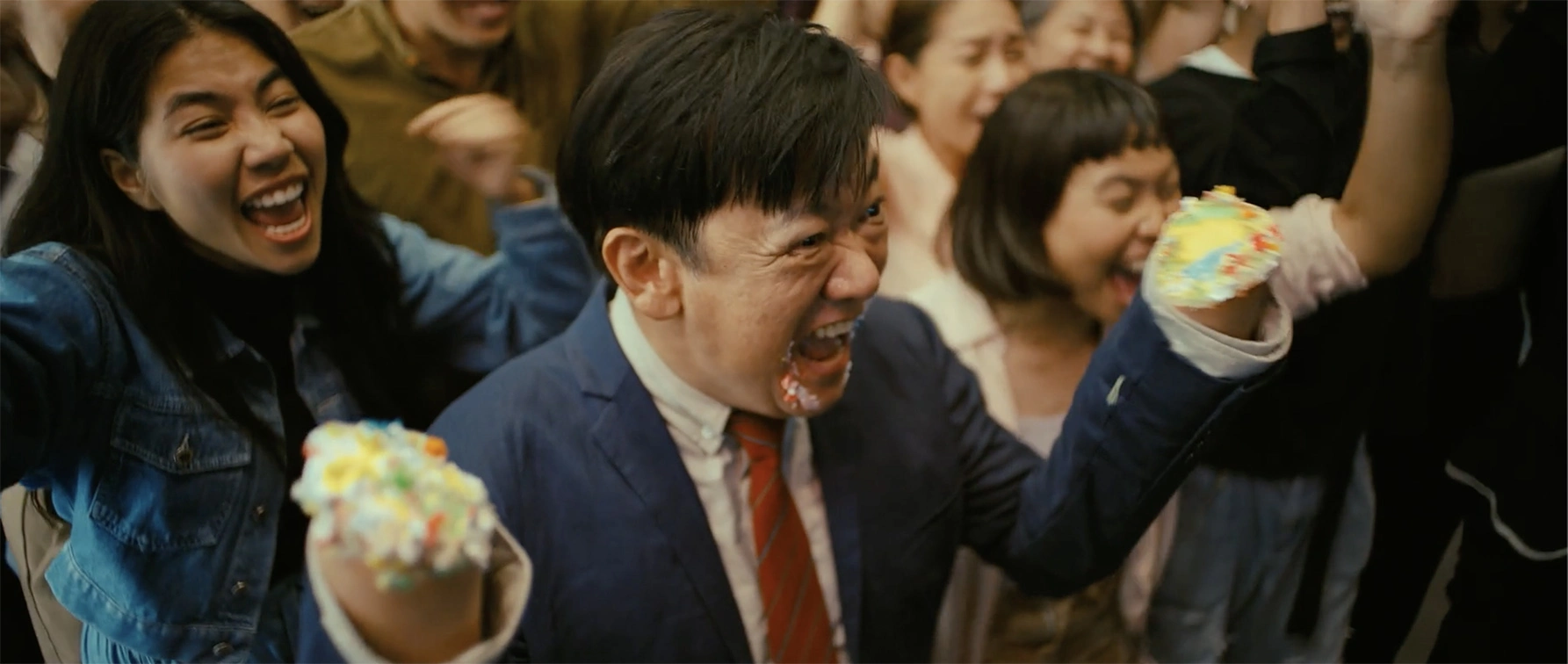 Escena de uno de los mejores comerciales de KFC, donde varios personajes sostienen trozos de pastel durante el spot Let There Be Cake.