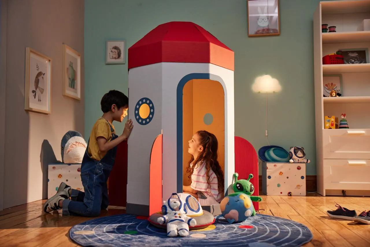 Mejor publicidad de IKEA: dos niños juegan dentro de un cohete de cartón en una habitación infantil decorada con muebles y accesorios de IKEA.