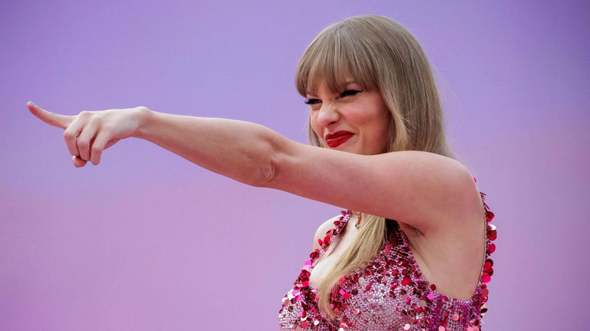 Taylor Swift sobre el escenario durante un concierto con iluminación morada.