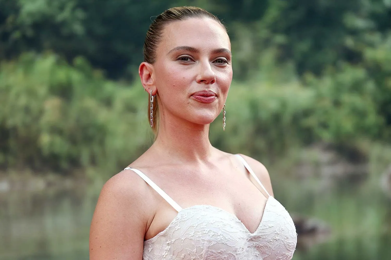 Scarlett Johansson con vestido blanco frente a un paisaje natural.