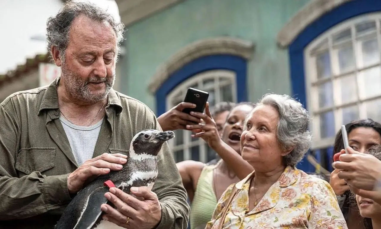 Jean Reno sostiene a un pingüino en una escena de "Mi Amigo El Pingüino".
