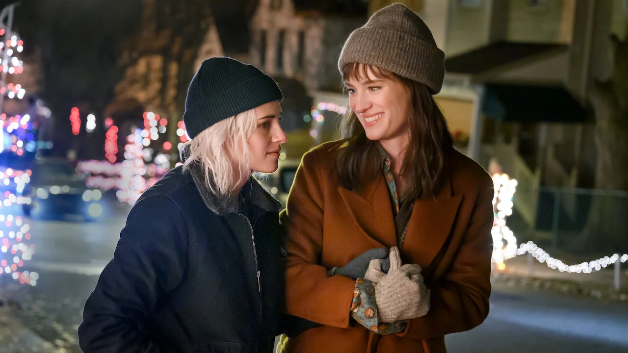 Dos mujeres caminando entre luces navideñas en una escena de película de Navidad.