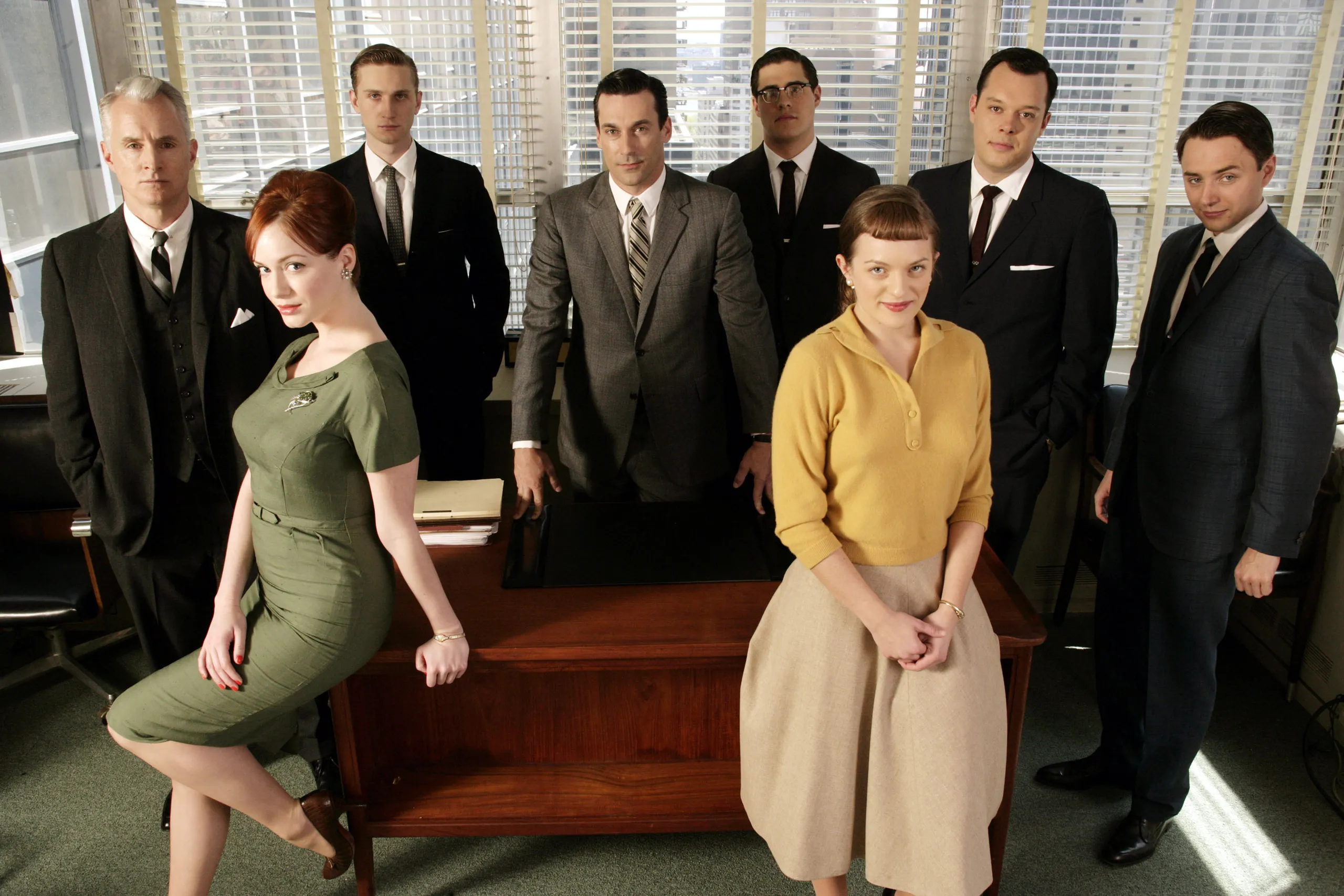 El elenco de Mad Men posa en una oficina, con Don Draper al centro y Peggy Olson y Joan Holloway en primer plano.