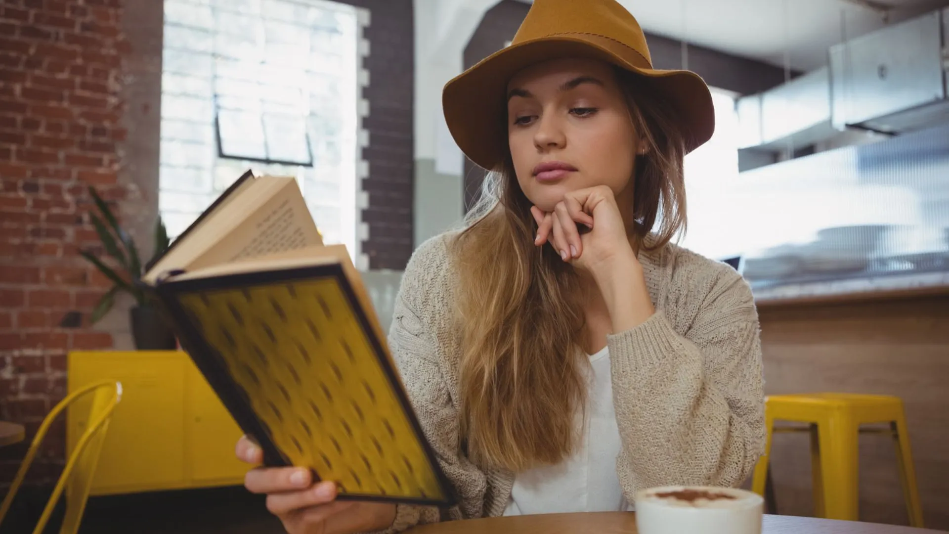 Mujer leyendo un libro en una cafetería para un artículo sobre libros de fantasía